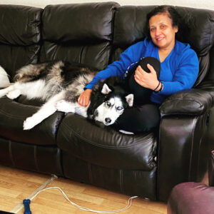 Shalini on sofa with her Husky dog